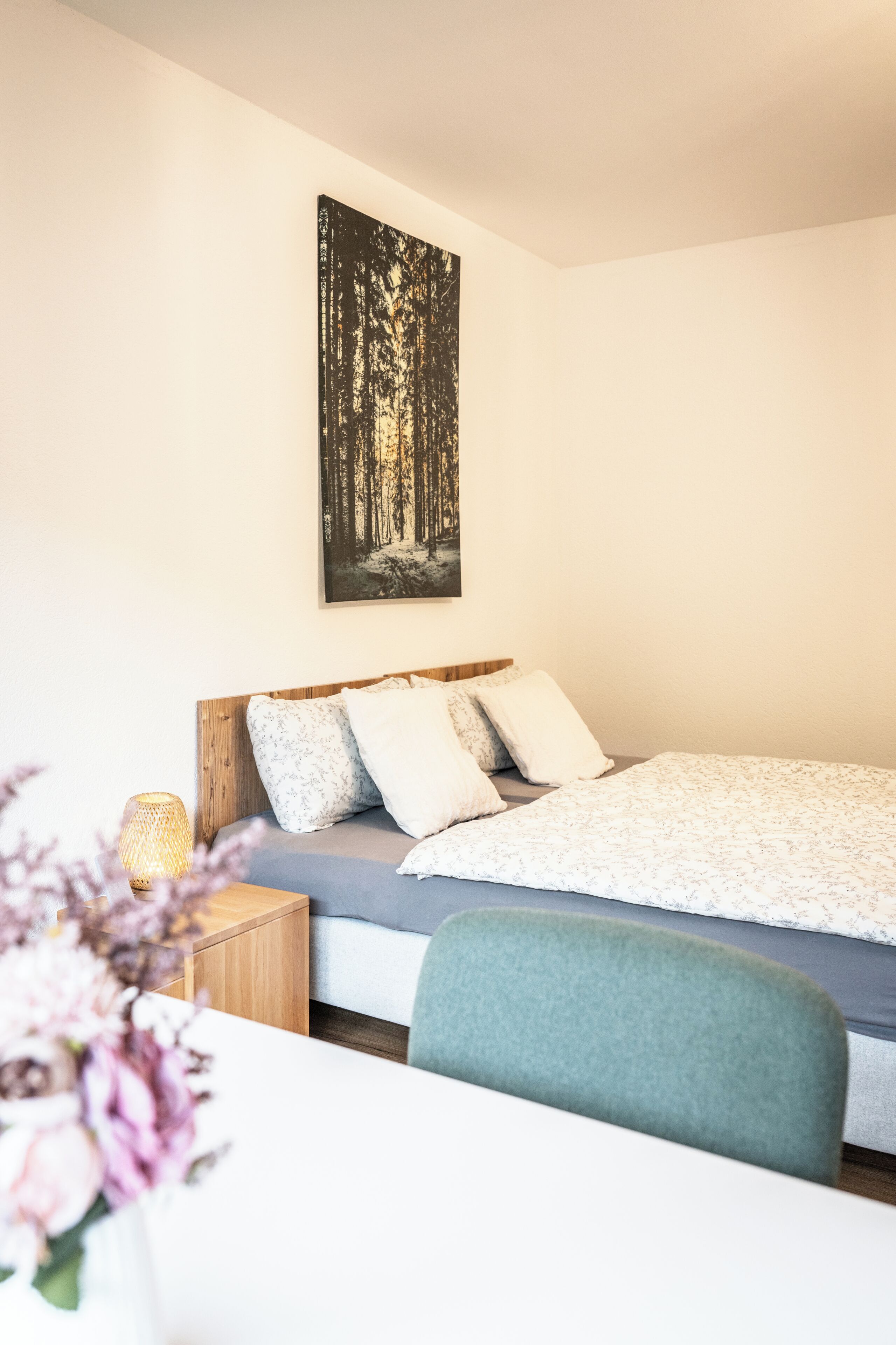 Ein Schlafzimmer mit einem Bett, einem Nachttisch und einem an der Wand hängenden Gemälde.