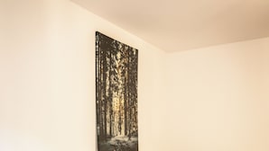 A bedroom with a bed, bedside table, and a wall-mounted painting. - Charming 1-bedroom riad in the heart of Freiburg im Breisgau (Freiburg im Breisgau)
