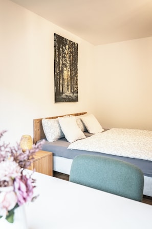 Una camera da letto con un letto, un comodino e un quadro appeso al muro.