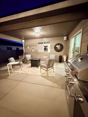 Ein Außenbereich mit Terrasse, Grill, Sitzgelegenheiten und einem wandmontierten Spiegel.
