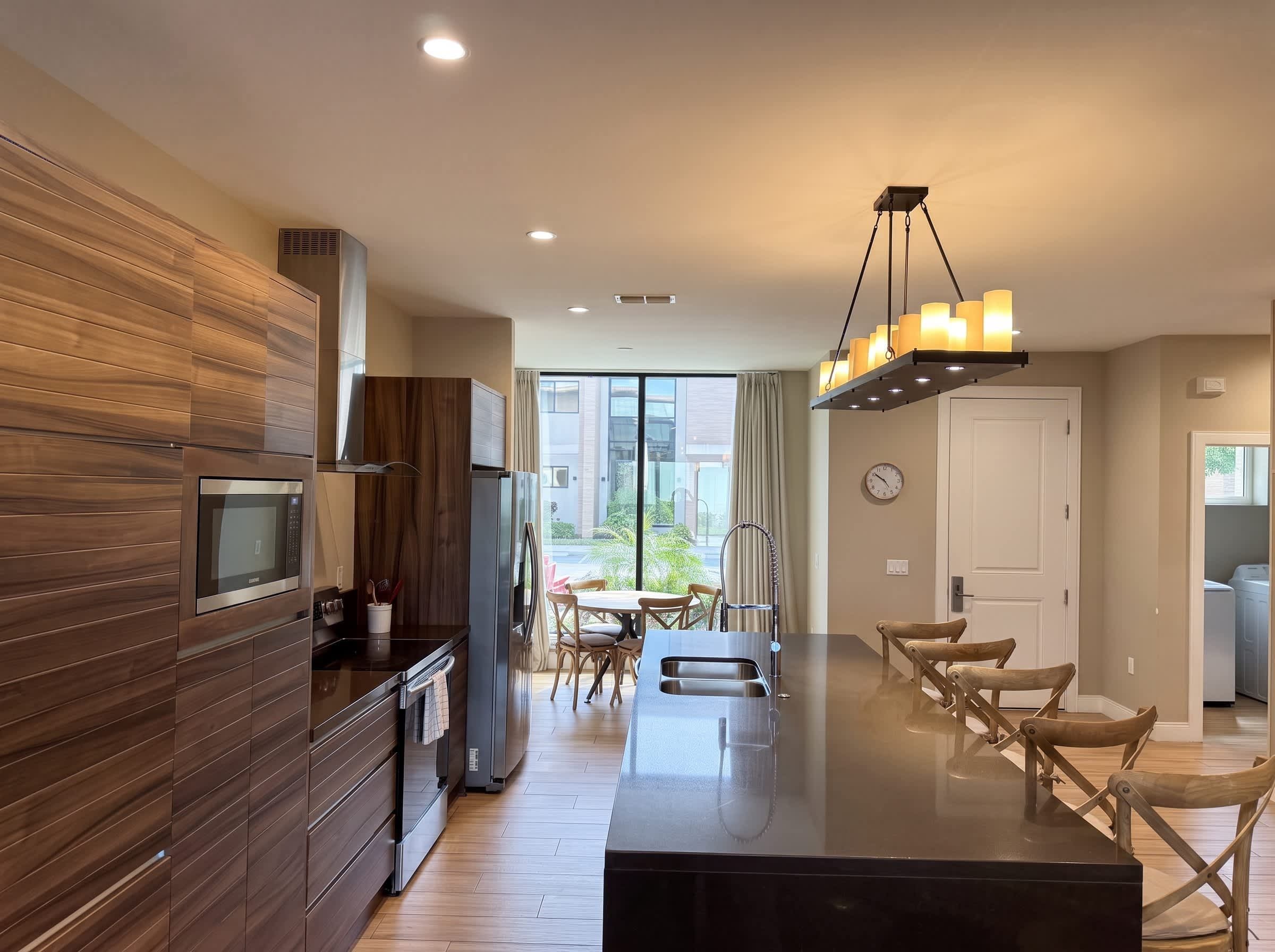 A modern kitchen with a built-in microwave, a stainless steel refrigerator, and a wooden backsplash.