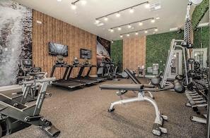 Un gimnasio con cintas de correr, bicicletas estáticas y máquinas de pesas.