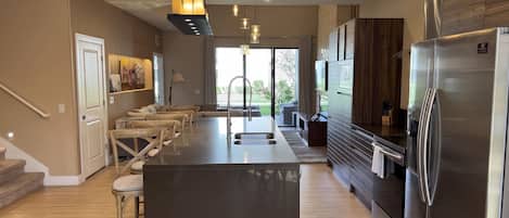 A modern kitchen with a central island, stainless steel appliances, and a view to the outdoors.