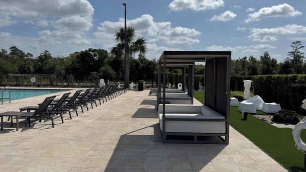 A poolside area with lounge chairs and a modern seating structure. - Magic Village Paradise 4BR (Kissimmee)