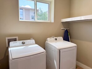 Una sala de bugaderia amb dues rentadores i assecadores frontals blanques, una finestra a la part superior i un escurapulles a la paret.