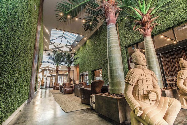 A lobby with a green wall, a palm tree, and a statue. - Magic Village Paradise 4BR (Kissimmee)