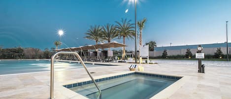 A swimming pool with a sunken area, lounge chairs, and palm trees.