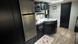 A compact kitchen with a built-in oven, a refrigerator, and a microwave.