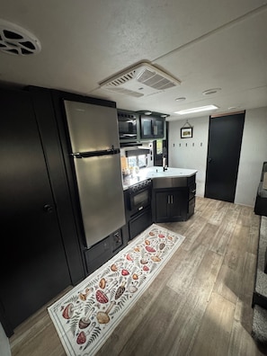 A compact kitchen with a built-in oven, a refrigerator, and a microwave.