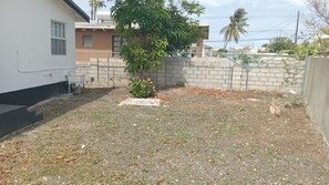 A fenced yard with a small tree, a concrete block, and a metal grate. - Short walk to beach, nearby supermarket, close to Oistins and other attractions. (Silver Sands)