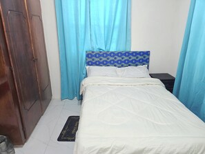 A bedroom with a bed, curtains, a headboard, a nightstand, and a wooden wardrobe. - Short walk to beach, nearby supermarket, close to Oistins and other attractions. (Silver Sands)