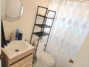 A bathroom with a sink, toilet, and a metal shelf unit. - Short walk to beach, nearby supermarket, close to Oistins and other attractions. (Silver Sands)