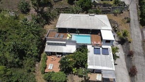 Una casa moderna con piscina, diverse terrazze e un ampio giardino.