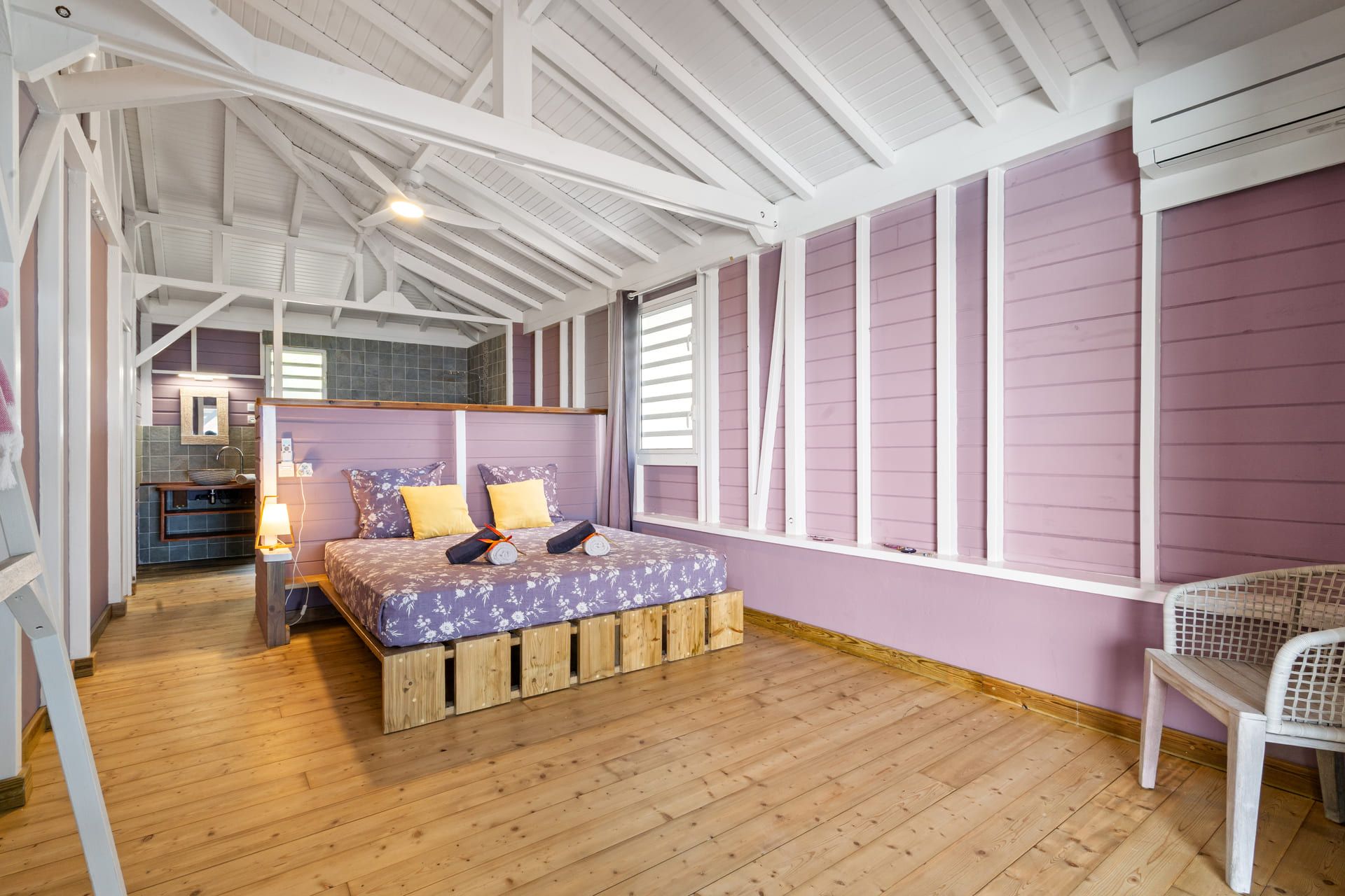 A room with a bed, a wooden floor, a window, and a chair.