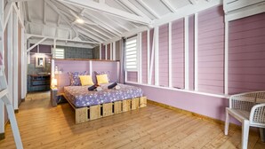 Una stanza con un letto, un pavimento in legno, una finestra e una sedia.
