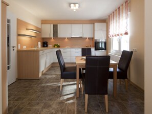 A compact kitchen with white cabinets, a dining table, and two chairs. - Holiday Home in Norderney With Wi-fi (Norderney)