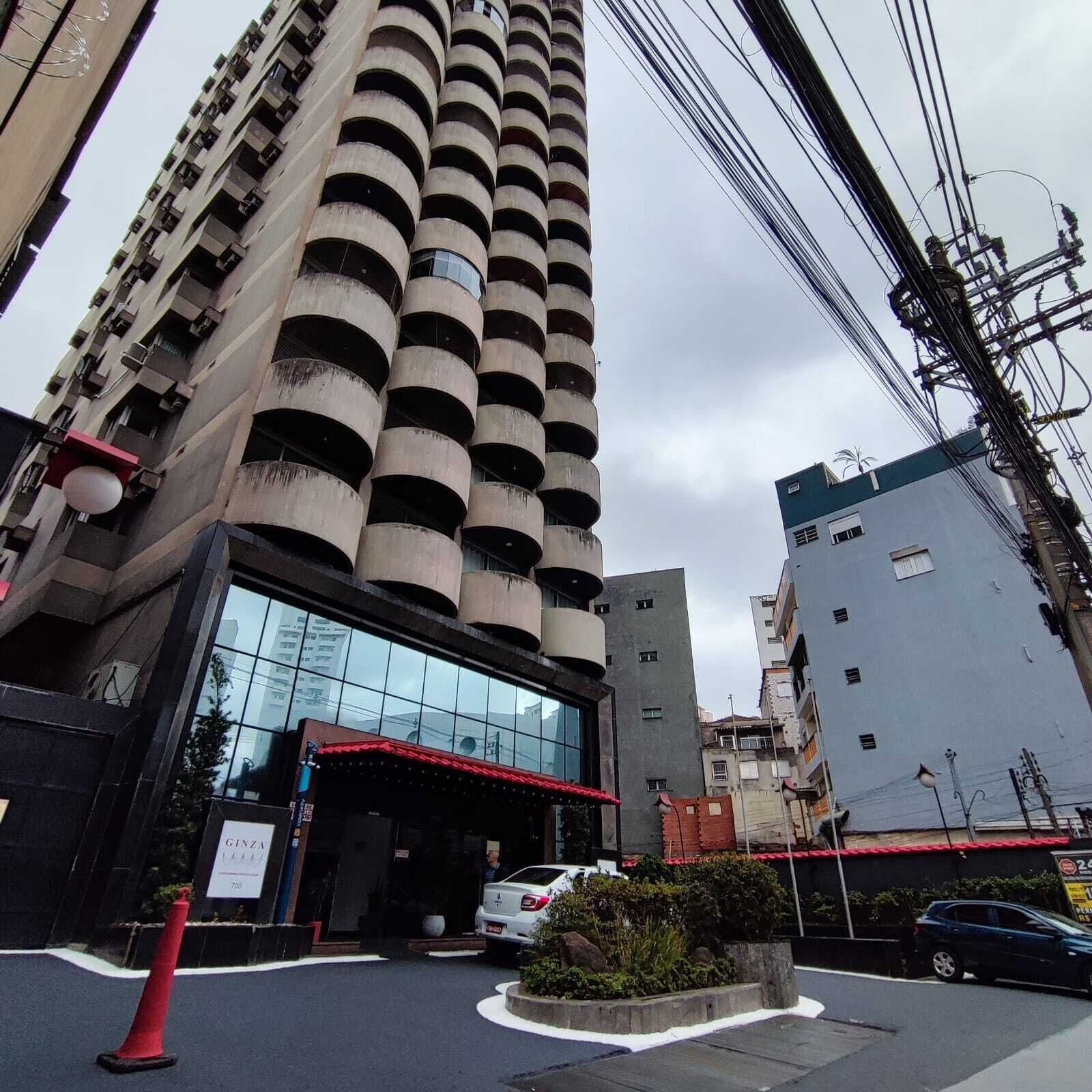 A high-rise building with a cylindrical central tower, a glass entrance, and a red awning.