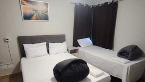 A hotel room with a large bed, a smaller bed, and a single bedside table. - Apartamento GoodLar Liberdade SP  (Liberdade São Paulo)