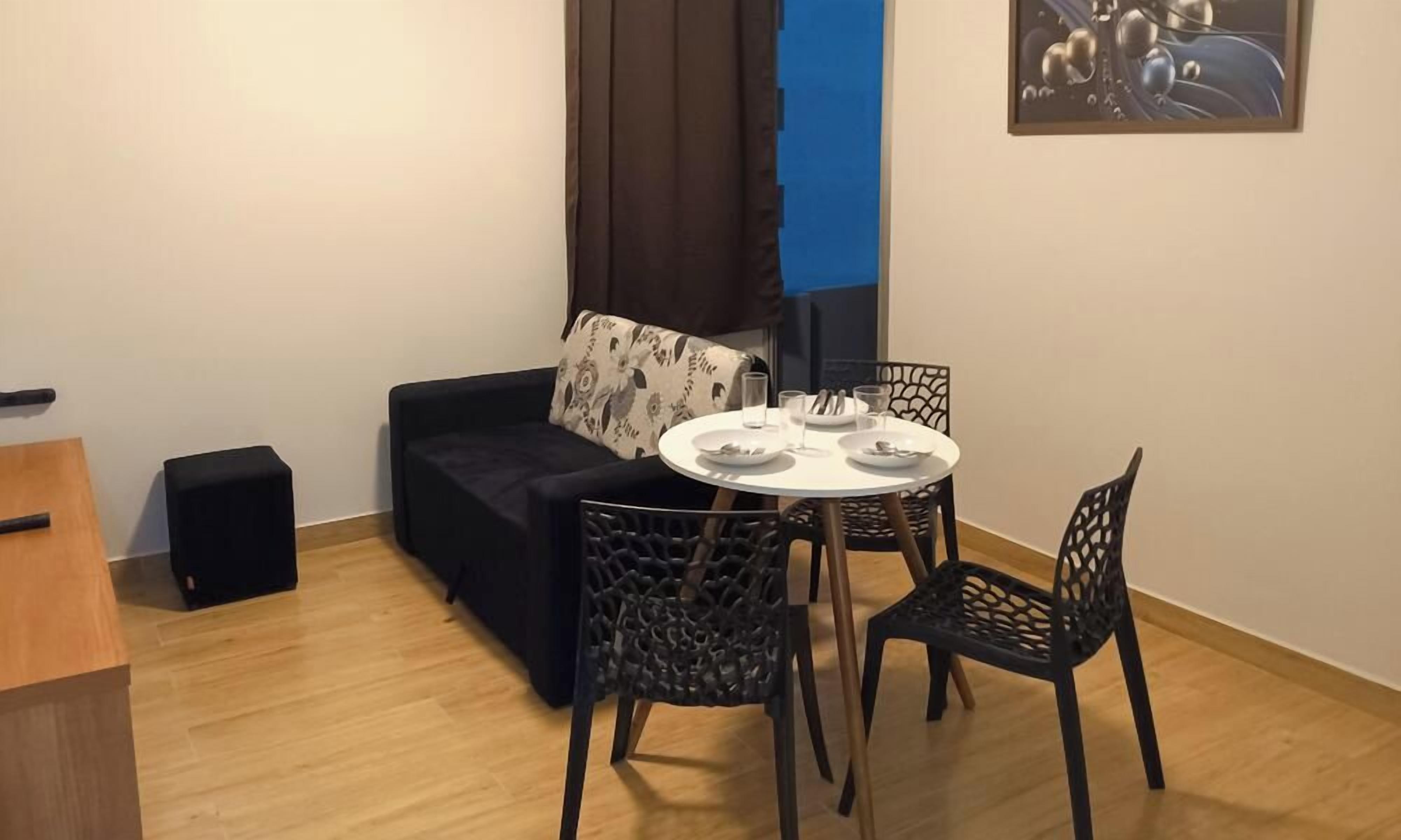 Un petit coin repas avec une table ronde, deux chaises, un canapé et un haut-parleur.
