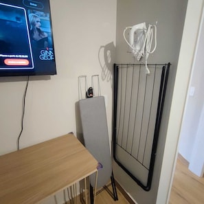 A room with a flat-screen TV mounted on the wall, a radiator, and a small table. - Apartamento GoodLar Liberdade SP  (Liberdade São Paulo)