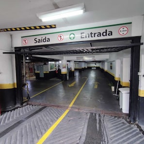Entrada a un aparcamiento con flechas direccionales, un cartel de 'Salida' y una señal de restricción de altura de 2,0 metros.