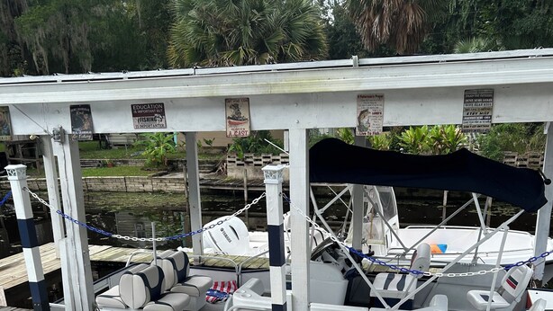 Eine Holzsteganlage mit überdachter Sitzgelegenheit und einem angestoßenen Boot in der Nähe.