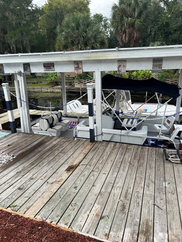 A wooden dock with a covered seating area and a boat moored nearby.
