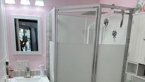 Ein Badezimmer mit Duschkabine, Toilette, Waschbecken mit Spiegel und einem Waschtisch mit Schränken.