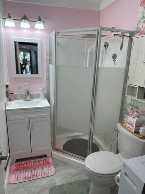 A bathroom with a shower enclosure, a toilet, a sink with a mirror, and a vanity with cabinets. - River Retreat “R&R” Water Front on The St. John’s River (Astor)