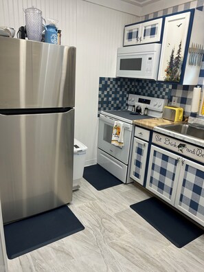 A modern kitchen with stainless steel appliances, a microwave, and checkered cabinets.