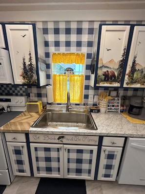 A kitchen with a checkered backsplash, a stainless steel sink, a toaster, and a coffee maker. - River Retreat “R&R” Water Front on The St. John’s River (Astor)
