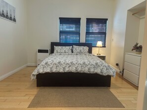A bedroom with a bed, bedside tables, a lamp, a heater, and a window with blinds. - A Charming Apartment inDTLA (Los Angeles)
