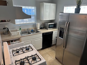 A modern kitchen with stainless steel appliances, a dishwasher, a microwave, and a gas stove. - A Charming Apartment inDTLA (Los Angeles)