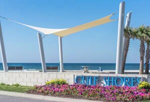 A beachfront property named 'Gulf Shores' with a clear view of the ocean, a white canopy structure, and a signboard. -  2Bed/2Bath Coastal Cove condo, Large pool! Minutes from Gulf Shores sandy coast (Gulf Shores)
