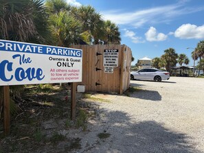 A private parking sign for 'The Cove' with a wooden dumpster and a car in the background. -  2Bed/2Bath Coastal Cove condo, Large pool! Minutes from Gulf Shores sandy coast (Gulf Shores)