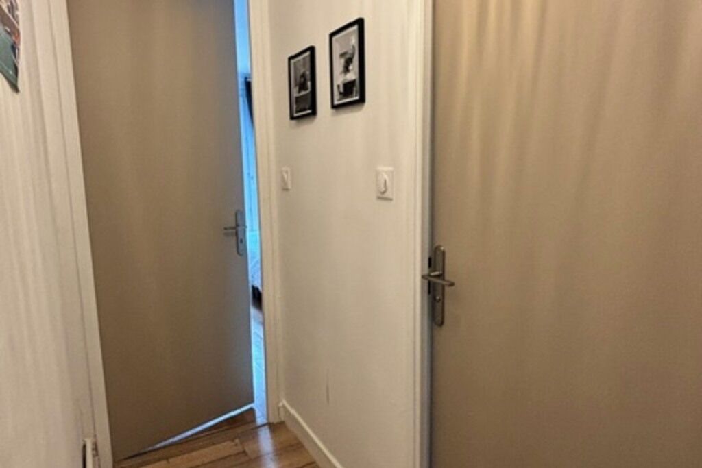 Un pasillo con una puerta a la derecha, un interruptor de luz y un cuadro colgado en la pared.