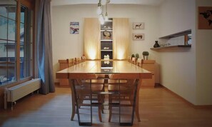 Une cuisine moderne avec une longue table en bois, des placards intégrés et une vue par la fenêtre.