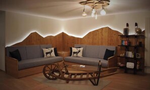 A modern living room with a wooden wall, a sofa set, a wooden coffee table, and a bookshelf. - STUNNING DESIGN APARTMENT IN THE HEART OF LAUTERBRUNNEN (Lauterbrunnen)
