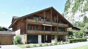 Ein zweistöckiges Holzhaus mit Balkonen, einer Garage und einem Blick auf die Berge.