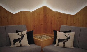 Un coin de pièce avec deux canapés gris, chacun orné d’un coussin représentant la silhouette d’un cerf.