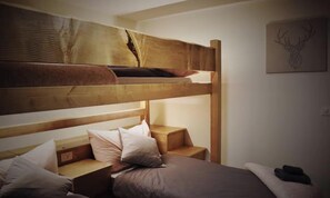 Een stapelbed met houten hoofdbord, een nachtkastje en een aan de muur hangend kunstwerk.