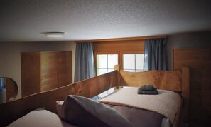 A single bed with a wooden headboard, a bedside table, and a window with curtains. - STUNNING DESIGN APARTMENT IN THE HEART OF LAUTERBRUNNEN (Lauterbrunnen)