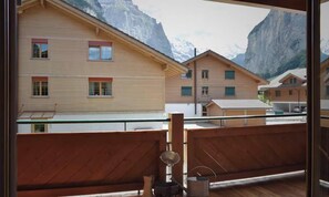 Un balcon en bois offrant une vue sur les maisons de montagne et un ciel dégagé.