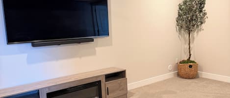 A modern living room with a flat-screen TV, wooden entertainment unit, a coffee table, and a ceiling fan.