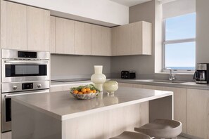 Una cocina moderna con electrodomésticos integrados, encimera de mármol y vistas al mar.