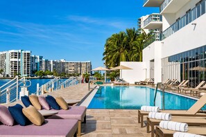 A poolside area with lounge chairs and umbrellas, a clear blue sky, and modern buildings in the background. - Hyde Beach House - Ocean View Luxury in Corner 2BR/2BA Suite, minutes to beach (Hollywood)