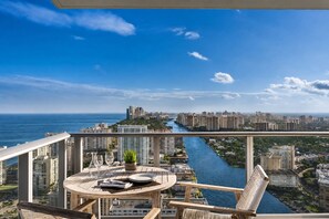 Un balcón con mesa lista para comer, con vistas a un paisaje urbano y un río.