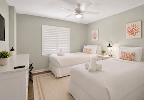 A bedroom with two beds, a ceiling fan, a window with blinds, a bedside table with a lamp, and artwork on the wall. - BEACHFRONT SUNSETS TO DIE FOR (Madeira Beach)