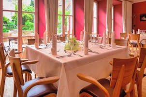 Comedor con mesa dispuesta para una comida, sillas y vistas a zonas verdes.