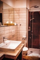 Un baño con lavamanos, espejo y cabina de ducha.